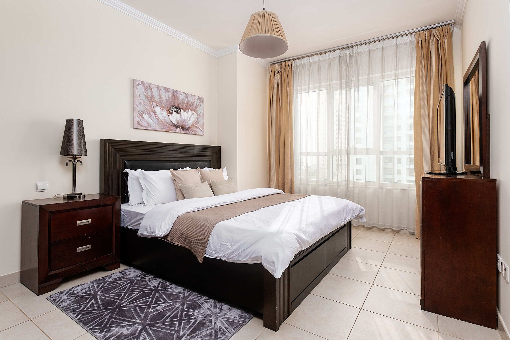 A bedroom with a bed, nightstand, lamp, and a painting on the wall.