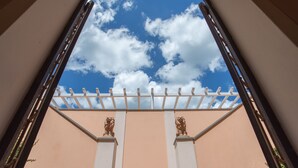 Blick durch ein Fenster auf einen wolkenlosen Himmel und eine weiße Pergola.
