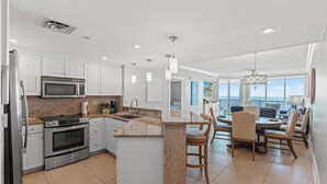 Una cocina moderna con armarios blancos, electrodomésticos de acero inoxidable y una isla central.