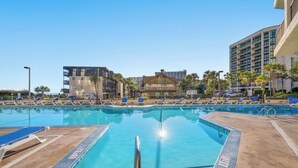 A swimming pool with lounge chairs and a building in the background. - Carolina Winds 1005-1BR OF Condo in Myrtle Beach (Myrtle Beach)