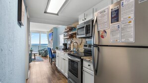 A kitchen with white cabinets, stainless steel appliances, and a view to the outside. - Carolina Winds 1005-1BR OF Condo in Myrtle Beach (Myrtle Beach)