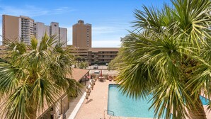 Un hôtel doté d’une piscine entourée de palmiers, d’un parking et offrant une vue sur les grands immeubles qui se dressent à l’arrière-plan.