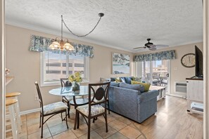 Relax in this open-plan living space with a dining area and seating area, featuring a sofa, dining table, and ceiling fan.