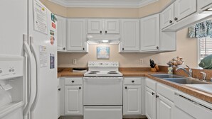 Une cuisine avec des meubles blancs, une cuisinière et un évier.