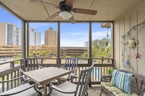 Enjoy a city view from this balcony with a table and chairs, ceiling fan, and decorative elements.
