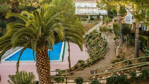 A pool area with a palm tree, a staircase, and a building with balconies. - AE-1 Charming Apartment in El Golfet (Calella de Palafrugell)