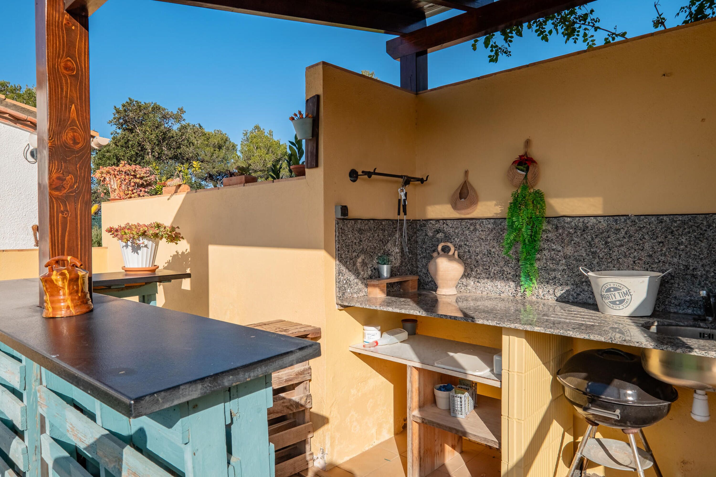 A kitchen with a granite countertop, a hanging pot rack, and a built-in sink.