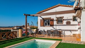 Una casa amb piscina, mobles de terrassa i vistes a les muntanyes.