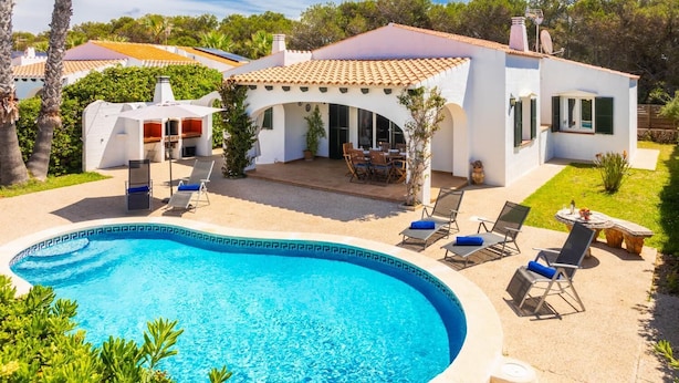 Ett modernt hus med en swimmingpool, utomhusmöbler och en uteplats.