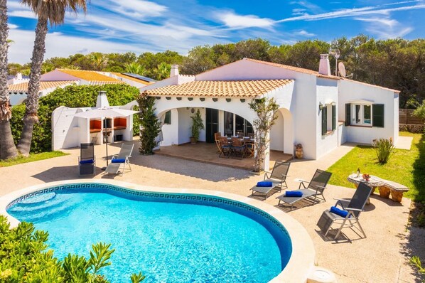 Una casa moderna con piscina, mobiliario exterior y zona de patio.