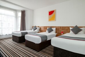 Une chambre d’hôtel avec deux lits, une moquette à rayures, une fenêtre avec des rideaux et une œuvre d’art murale.