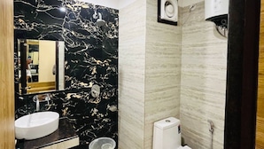 A modern bathroom with a black marble sink, a toilet, and a bidet. - The Fragrance Hotel (Reasi)