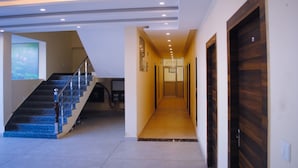 A modern interior with a staircase, a hallway, and a wooden door. - The Fragrance Hotel (Reasi)