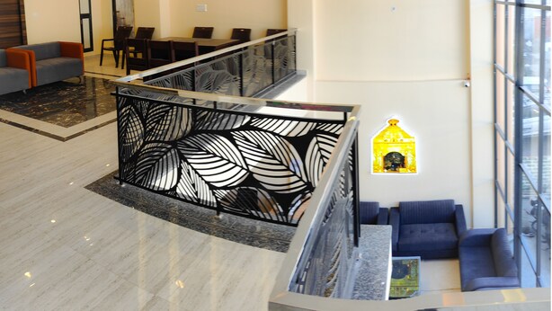 A modern hotel lobby with a marble floor, a staircase with a decorative railing, and a seating area with sofas. - The Fragrance Hotel (Reasi)