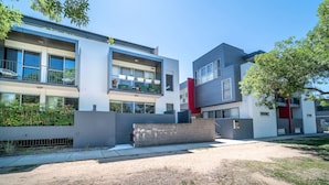 Un immeuble résidentiel moderne doté d’un toit plat, de grandes fenêtres et d’un balcon aménagé avec du mobilier d’extérieur.