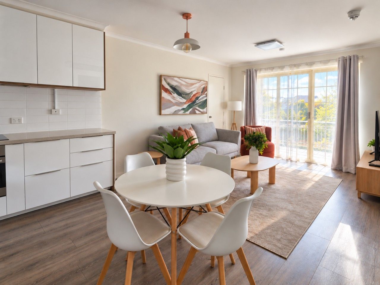 A modern living room with a round dining table, white chairs, a sofa, and a coffee table.