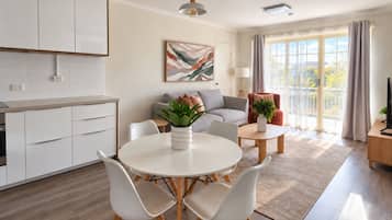 A modern living room with a round dining table, white chairs, a sofa, and a coffee table.