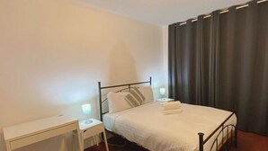 A single bed with a metal frame, white bedding, and two bedside lamps. - Quiet 2BR Apartment with Garden views in Griffith (Griffith)