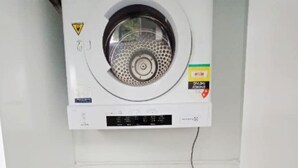 A wall-mounted washing machine and dryer unit with control panels and safety labels. - Quiet 2BR Apartment with Garden views in Griffith (Griffith)