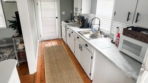 Una cucina moderna con mobili bianchi, un lavello in acciaio inossidabile e un forno a microonde.