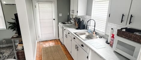 A modern kitchen with white cabinets, a stainless steel sink, and a microwave.