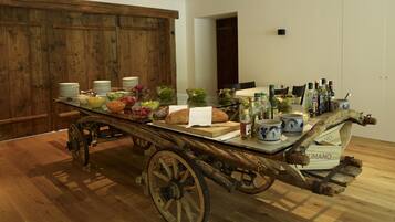 A dining table with a rustic wooden cart, various dishes, and bottles of beverages.