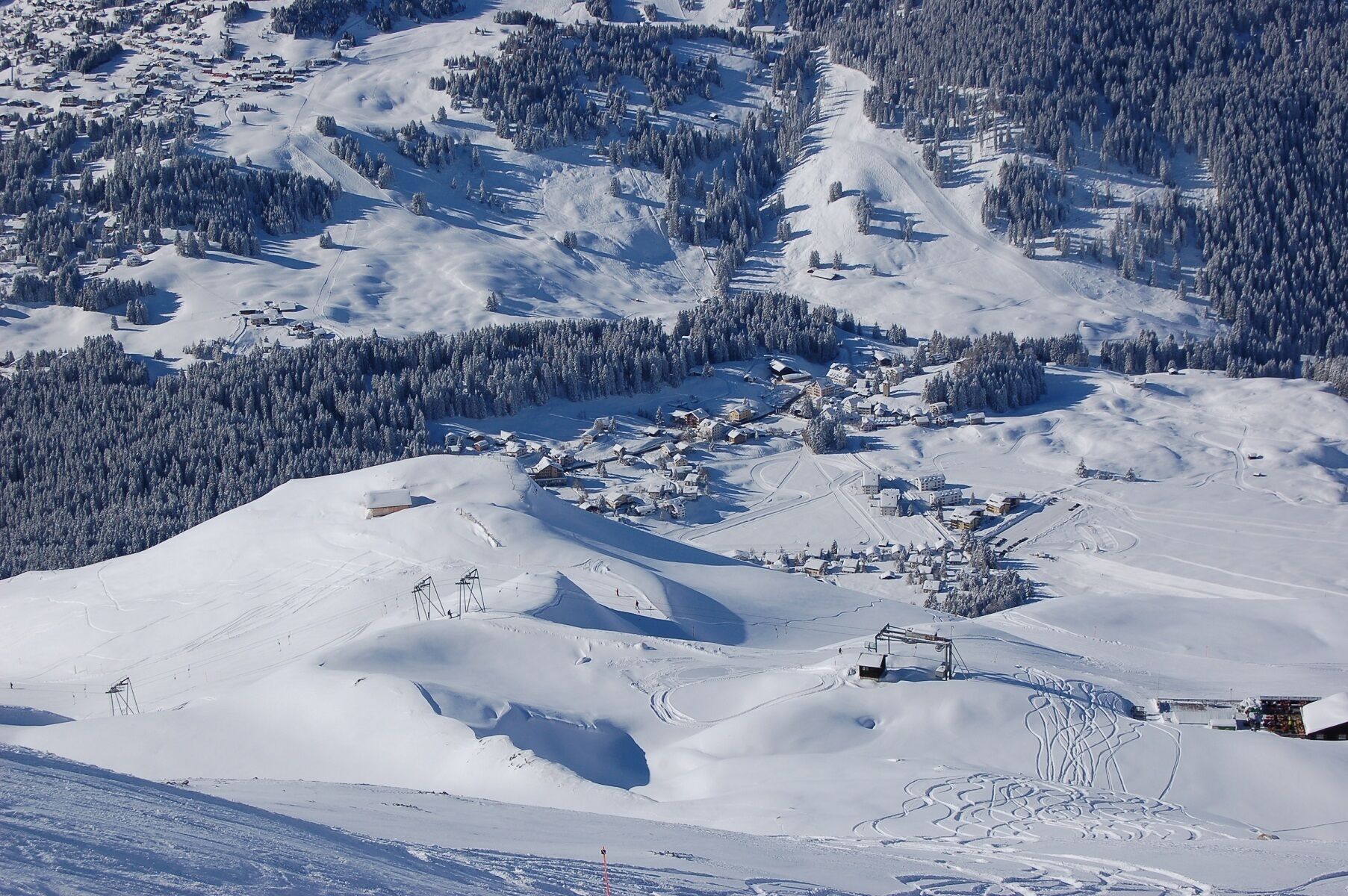 A snow-covered ski resort with ski lifts, trails, and buildings.