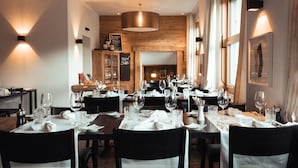 A restaurant with multiple tables set for dining, wooden walls, and modern lighting fixtures. - Hotel Alpina Parpan (Churwalden)