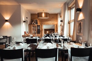 Un restaurante con varias mesas dispuestas para comer, paredes de madera e iluminación moderna.