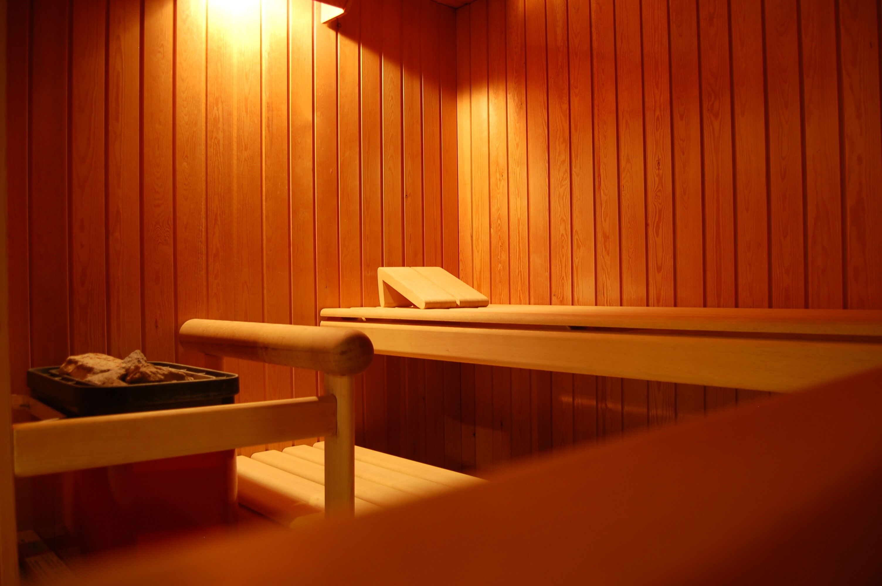 Un sauna avec des murs en bois et un banc.