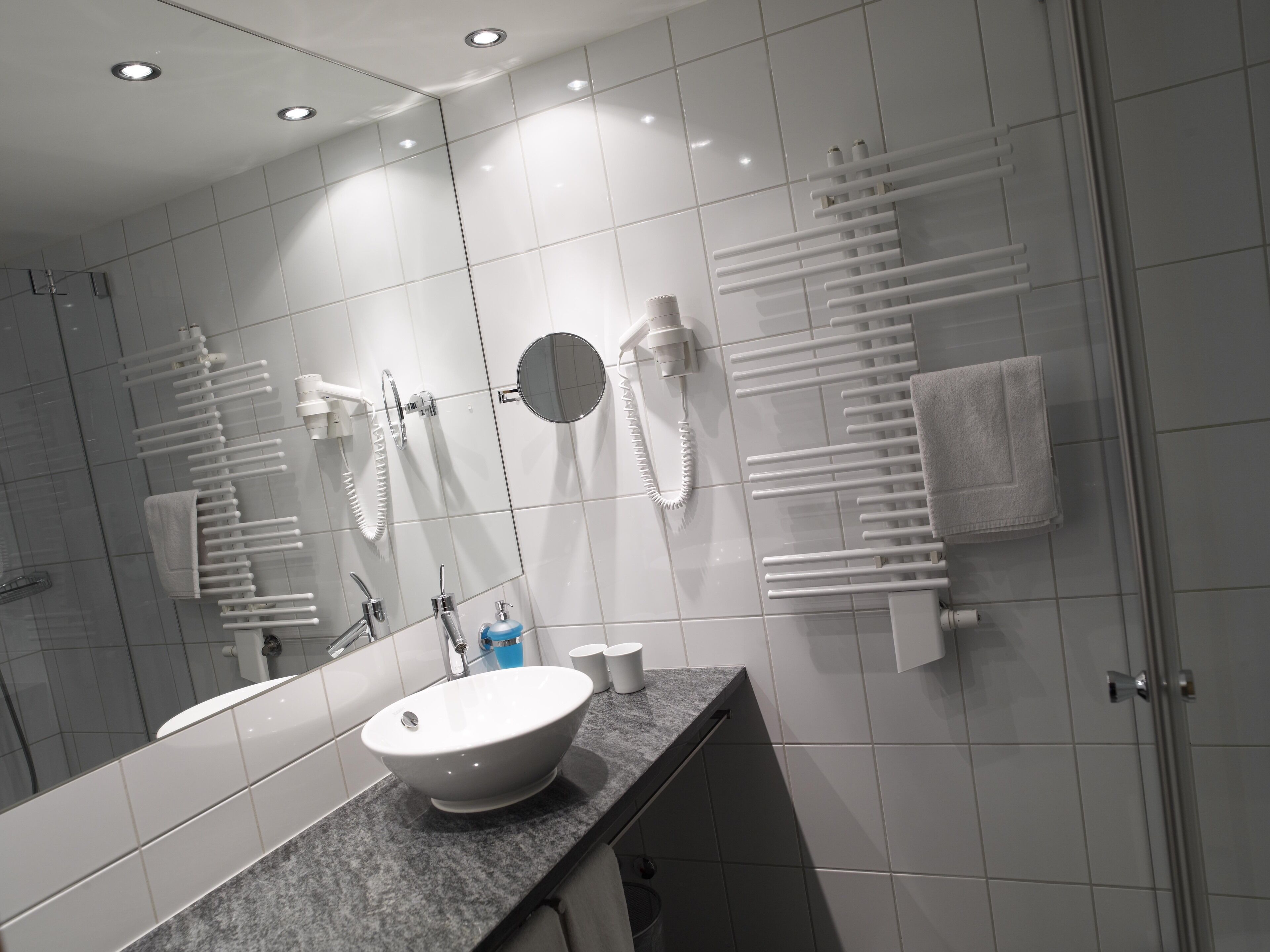 Une salle de bain moderne avec un grand miroir, un lavabo et un porte-serviettes.