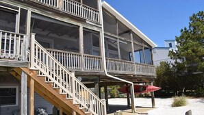 A multi-story house with a wooden deck and a staircase leading to a balcony.