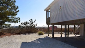 A building with a covered outdoor area, a gravel driveway, and a fenced property.