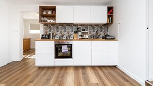 Une cuisine de taille réduite avec des meubles blancs, un four encastré et un plan de travail en bois.