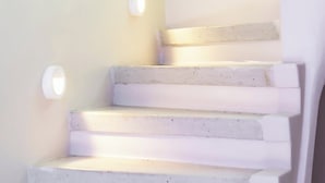 Un escalier avec des marches blanches et des luminaires fixés au mur.