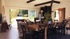 A spacious dining area with a large wooden table and chairs, a fireplace, and a view of the outdoors. - House on large terrain between beach & salt marshe (La Couarde-sur-Mer)