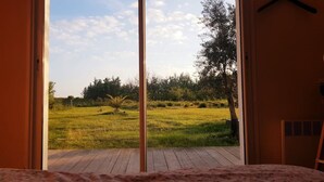 A room with a large window overlooking a grassy field and trees. - House on large terrain between beach & salt marshe (La Couarde-sur-Mer)
