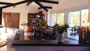 A spacious living area with a high ceiling, a dining table, and a bookshelf. - House on large terrain between beach & salt marshe (La Couarde-sur-Mer)