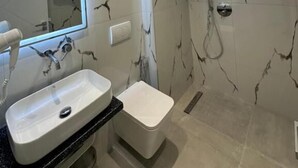 A modern bathroom with a marble wall, a sink, a toilet, and a shower. - Noa Boutique Hotel (Ksamil)