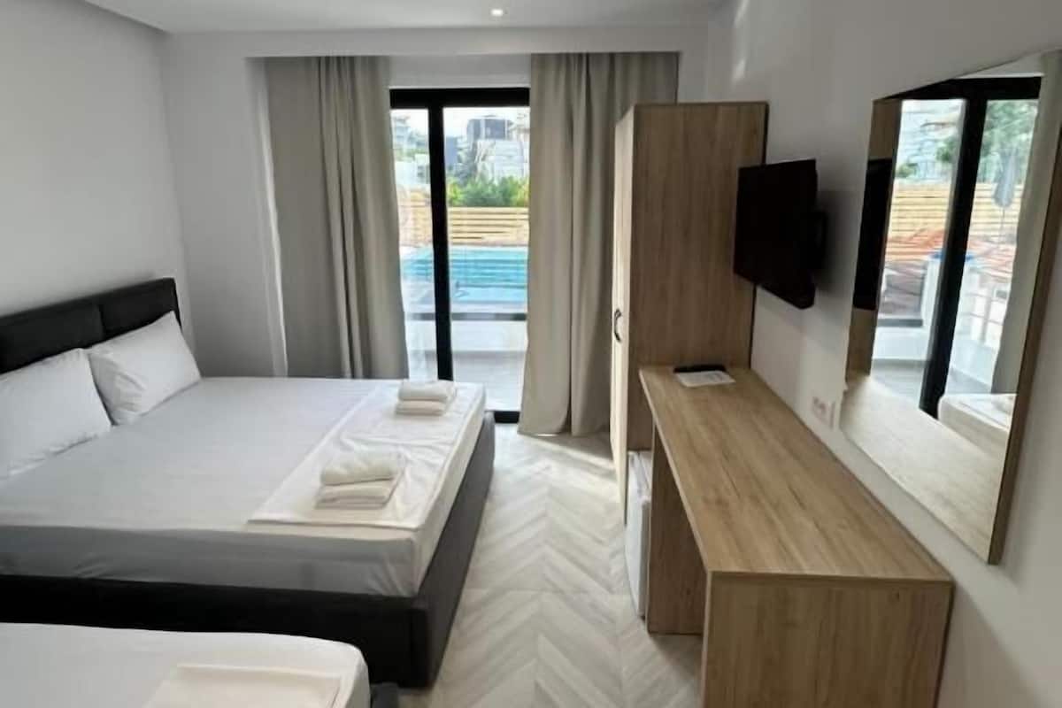 A modern hotel room with a bed, a desk, a TV, and a view of the outside.