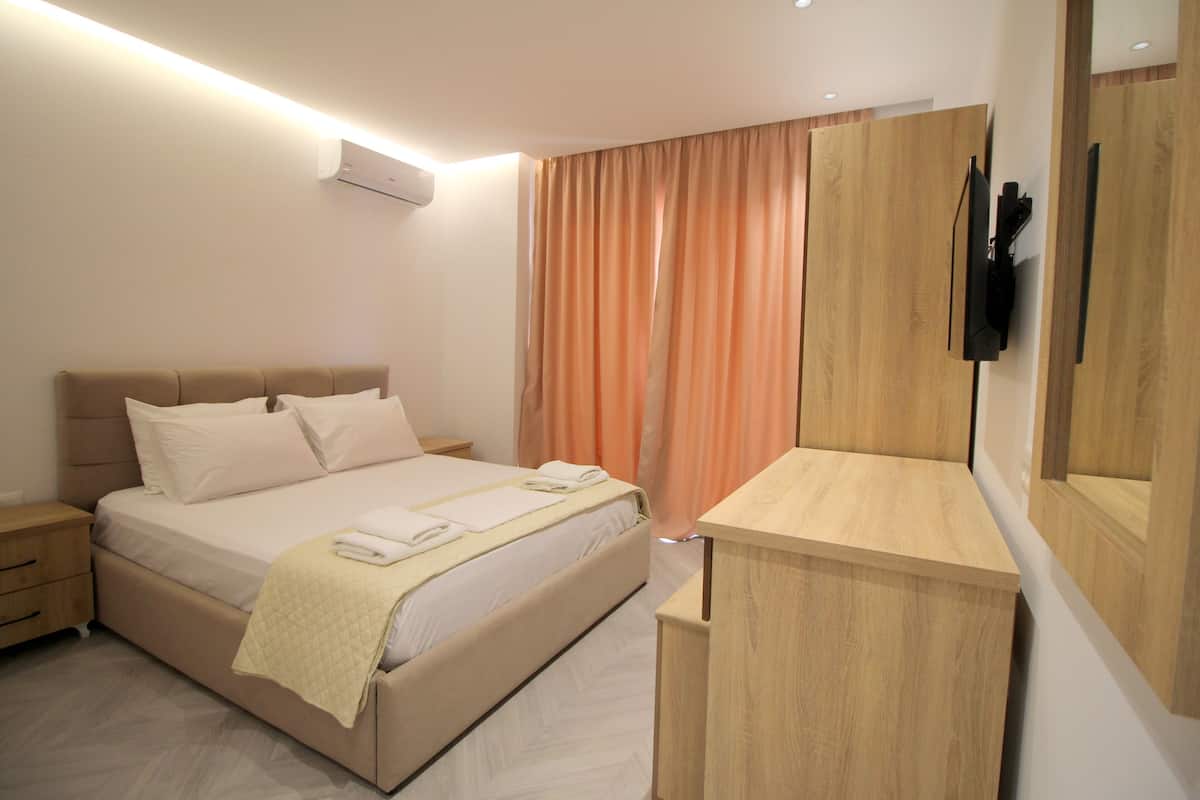 A modern bedroom with a bed, bedside tables, a wooden dresser, and an air conditioning unit.