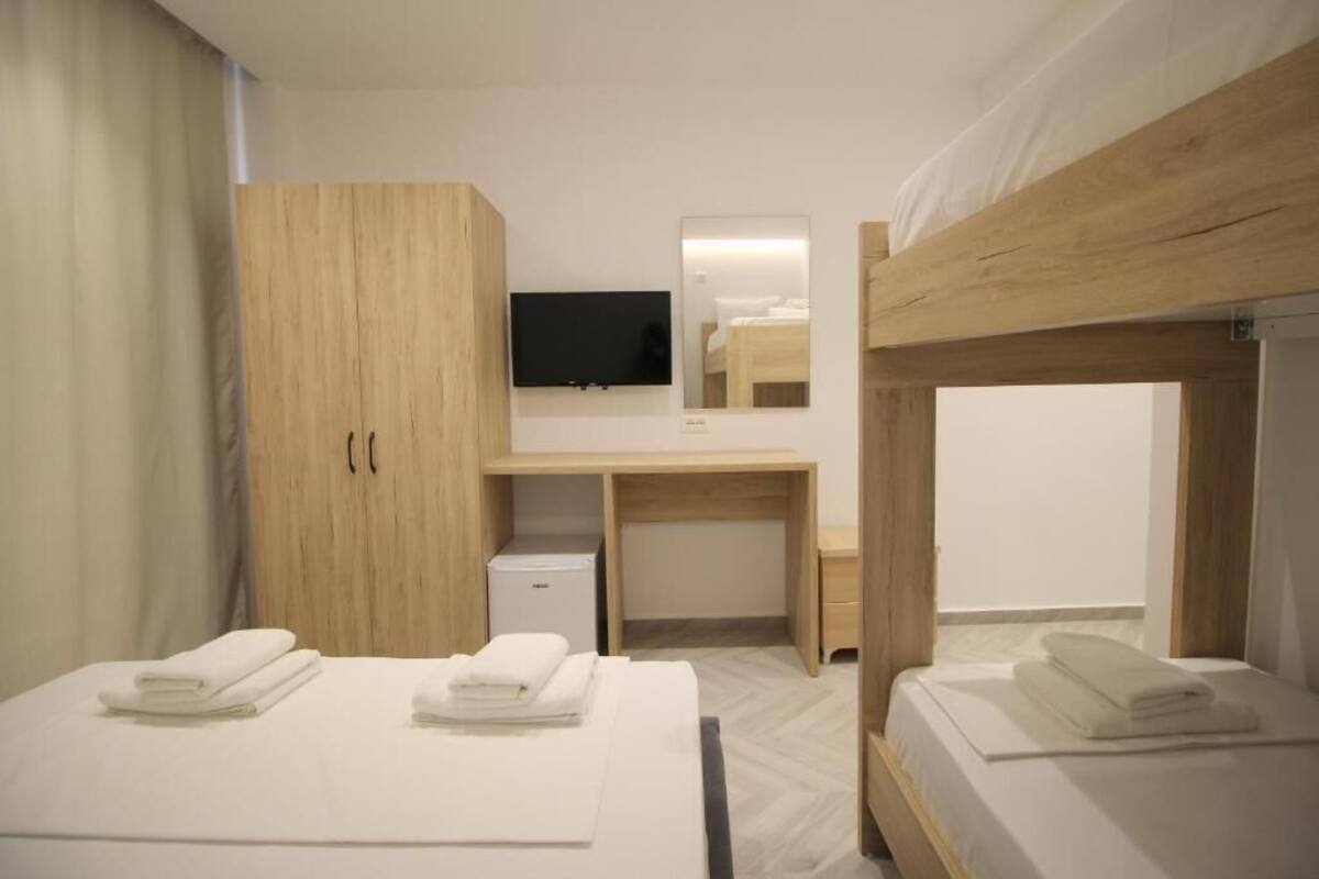 A hotel room with bunk beds, a desk, a television, and a wardrobe.