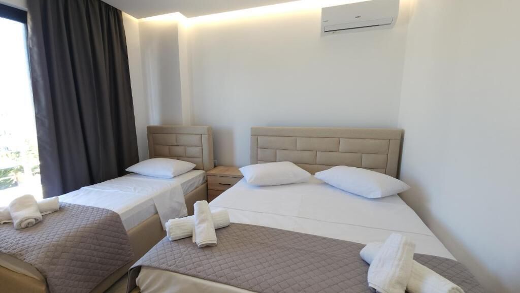 Une chambre d’hôtel avec deux lits, chacun doté d’une tête de lit, d’une table de chevet et d’une fenêtre avec des rideaux.
