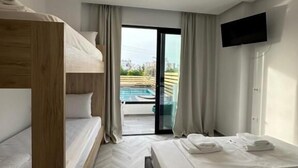A hotel room with bunk beds, a flat-screen TV, a sliding glass door to a pool, and a herringbone floor pattern. - Noa Boutique Hotel (Ksamil)