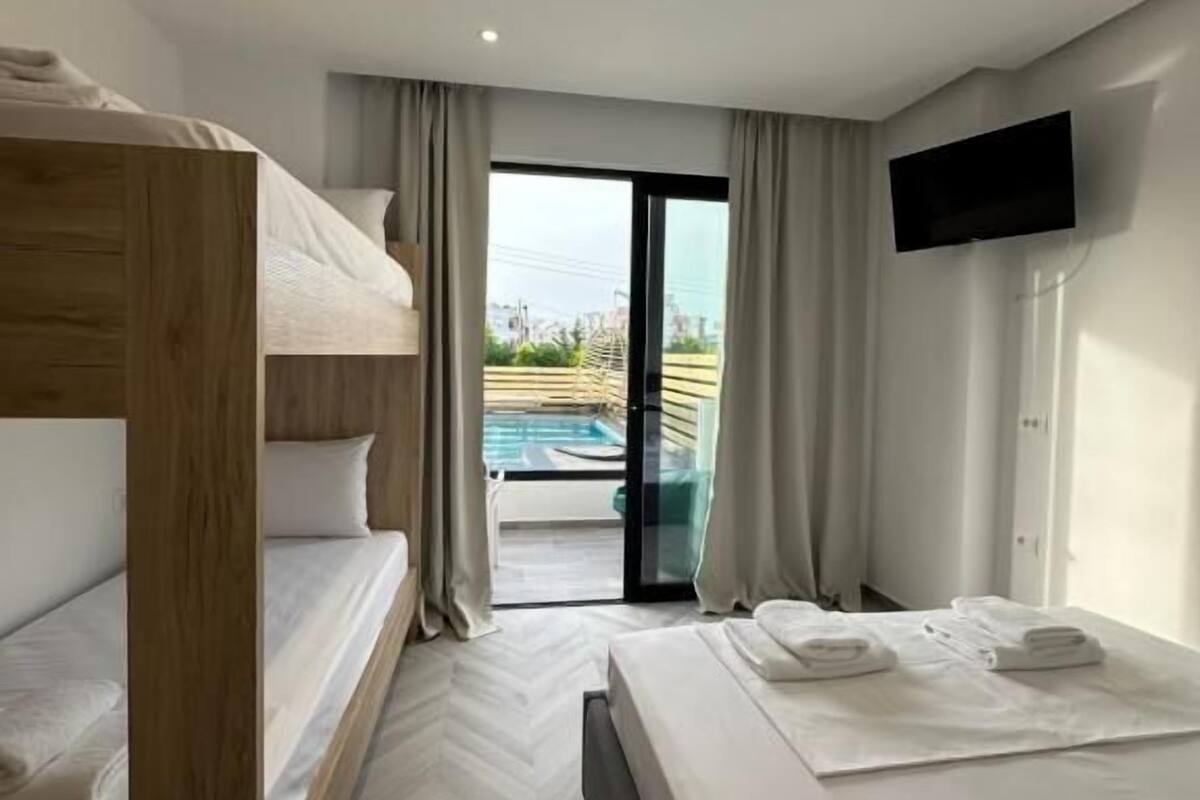 A hotel room with bunk beds, a flat-screen TV, a sliding glass door to a pool, and a herringbone floor pattern.