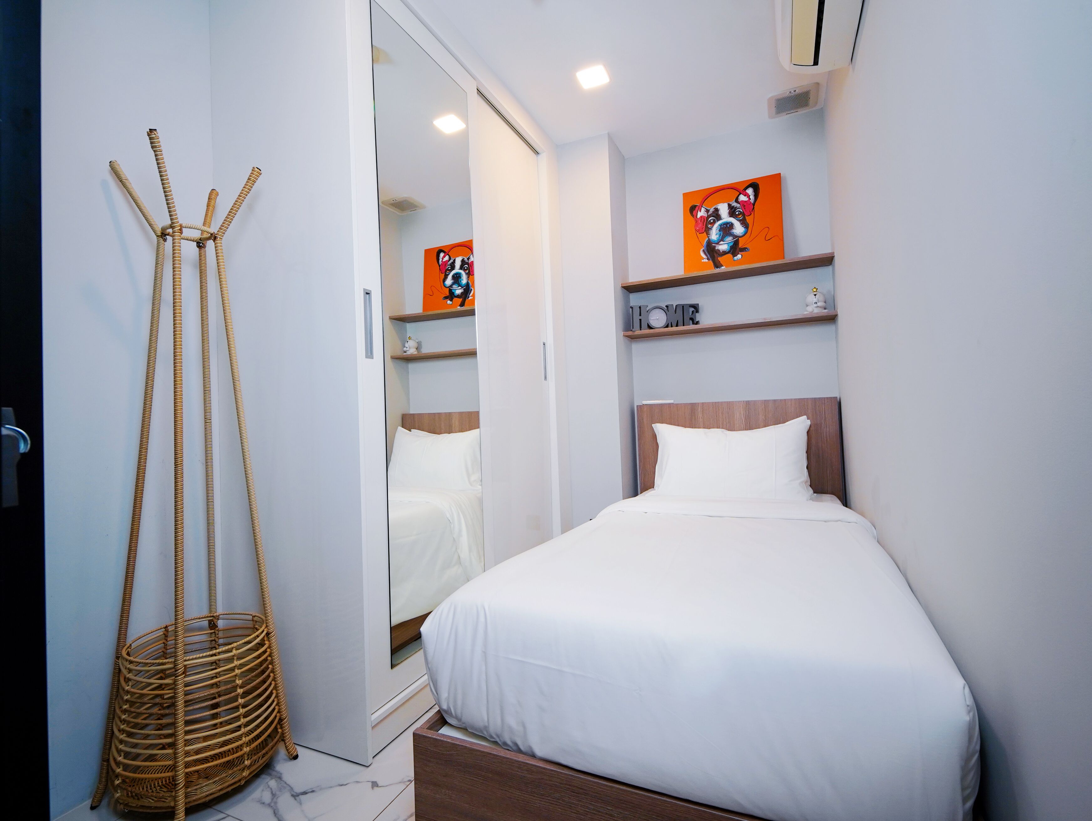 A modern bedroom with a bed, a wicker basket, and artwork on the wall.