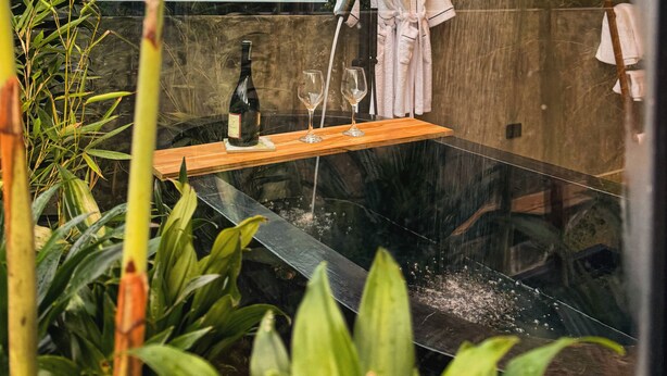 A modern bathroom with a rain shower, a wooden shelf with a bottle and glasses, and a towel rack. - Almazewá (Ubaque)