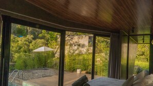 A modern bedroom with a large bed, a view of a swimming pool, and a lush garden outside. - Almazewá (Ubaque)