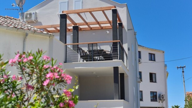 Un immeuble de deux étages doté d’un balcon à l’étage supérieur, d’une antenne parabolique et de climatiseurs.