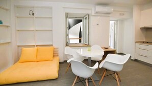 Une pièce moderne et bien éclairée, comprenant un canapé, une table à manger avec des chaises et un coin cuisine.